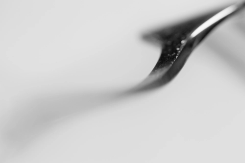 a double arch mostly out of focus swinging from the bottom left to the top right corner of the image in monochrome grey.