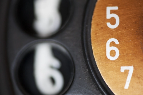 a closeup of a dial plate of an old telephone showing the numbers 5, 6 and 7.