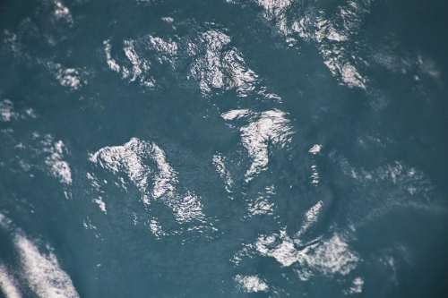 textures of dark turquoise colour with bright highlights - like the agitated sea from an aerial view.