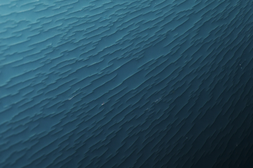 a gradient of turquoise to black from the top left to the bottom right corner of the image. broken lines are texturizing the surface perpendicular to the gradient.